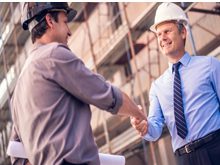 Two men shaking hands in front of a building.