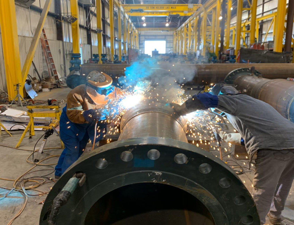 A group of people welding in an industrial setting.