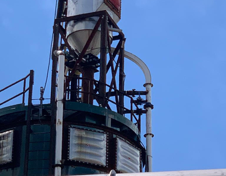 A tall tower with many pipes on top of it.