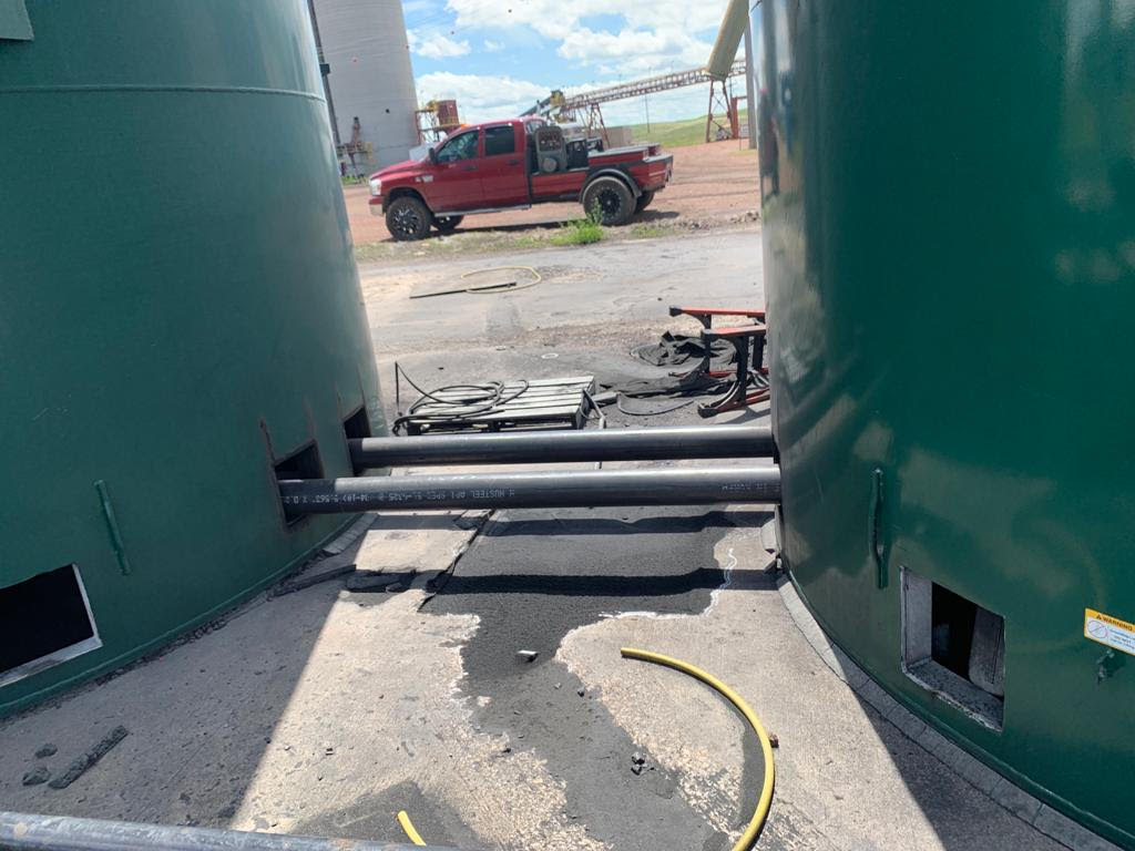 A truck is parked in front of a green tank.