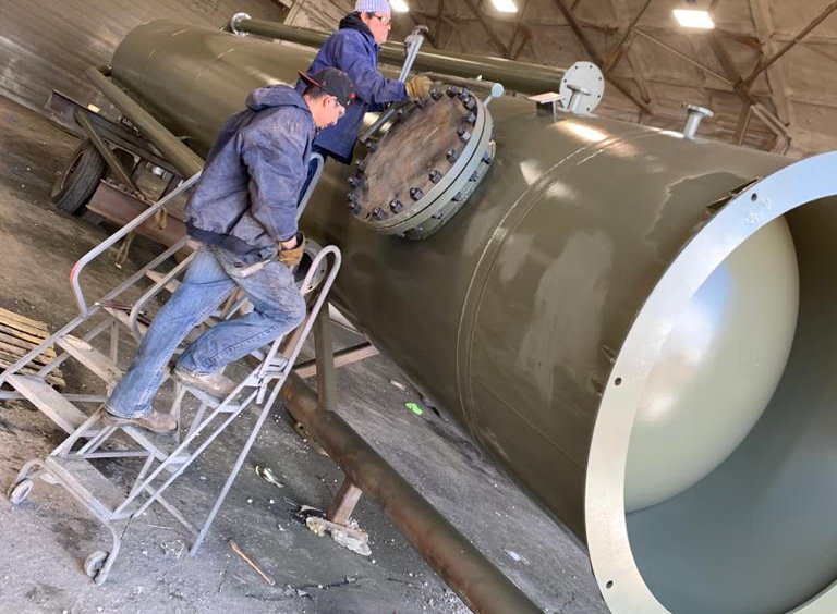 A man on some steps in front of a large pipe.