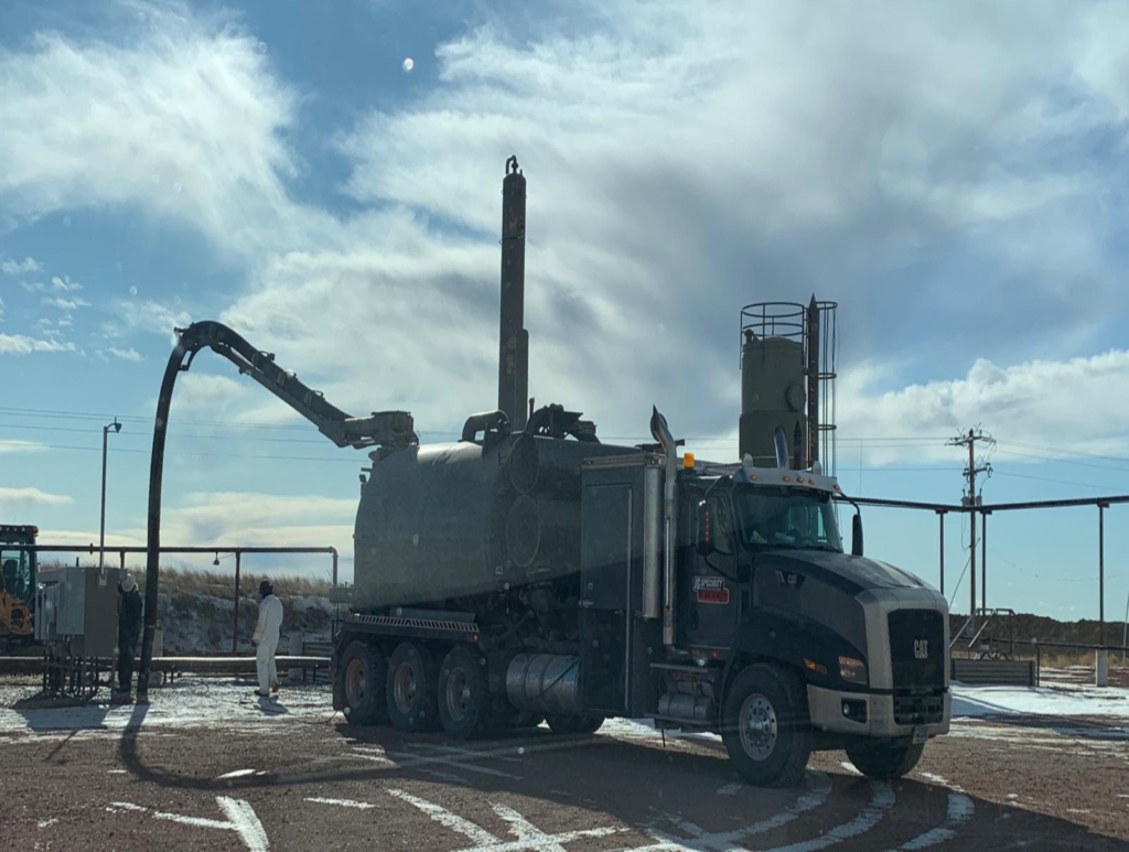 A large truck with a hose attached to the back of it.