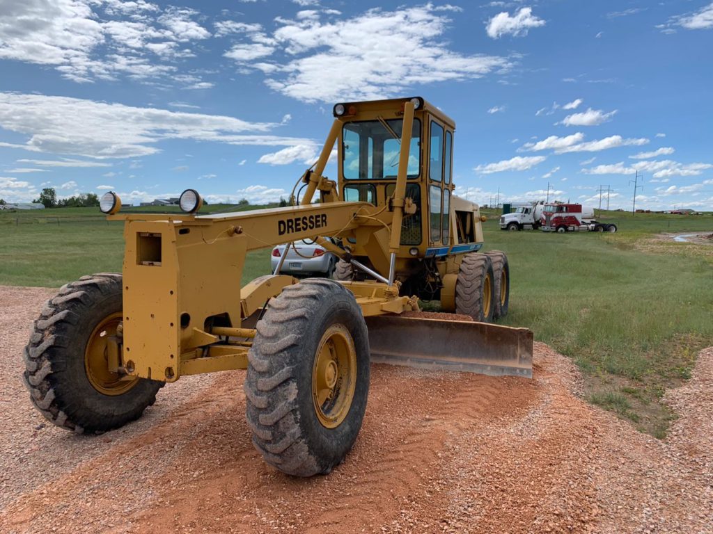 A yellow tractor is parked on the dirt.