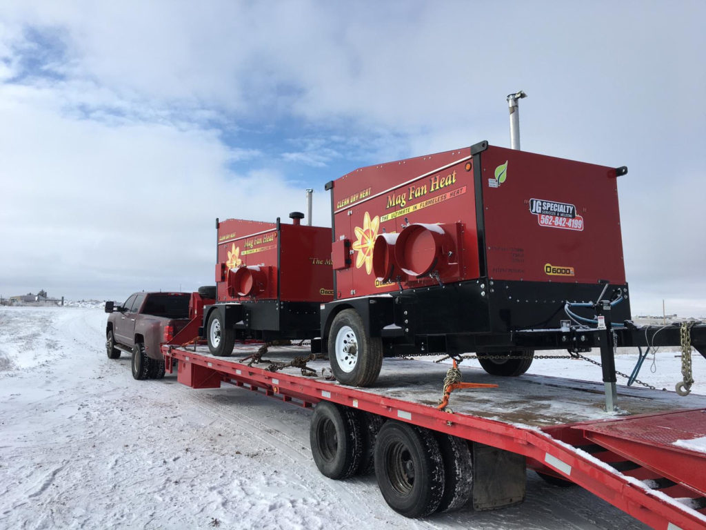 A red truck is carrying two large generators.