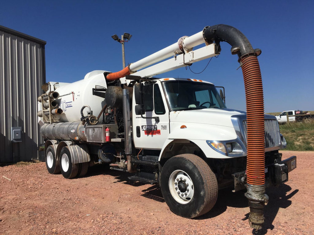 A white truck with a pipe attached to the back of it.