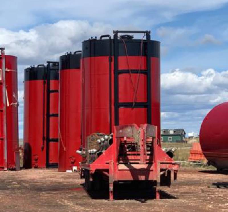 A red trailer with several large tanks in the background.