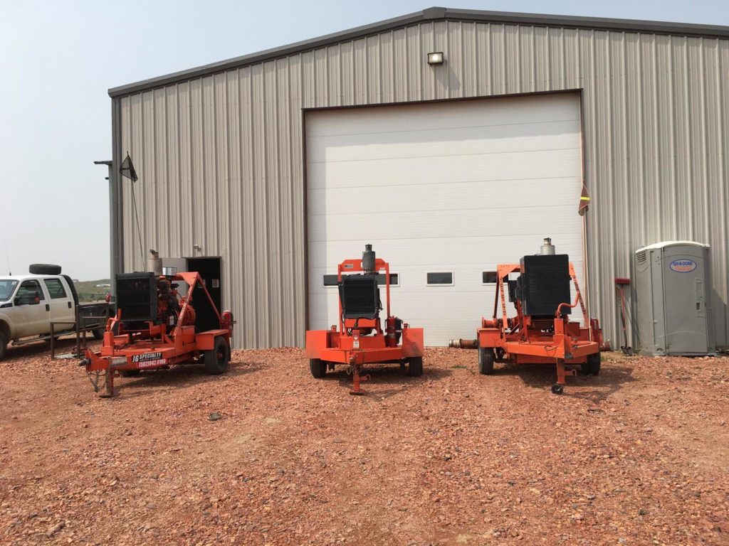 Three large machines are parked in front of a building.