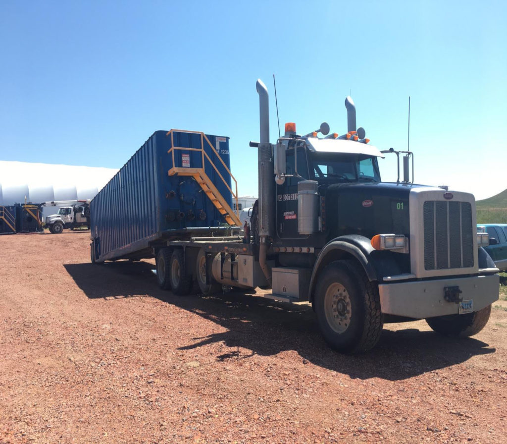 A large truck is parked on the dirt.