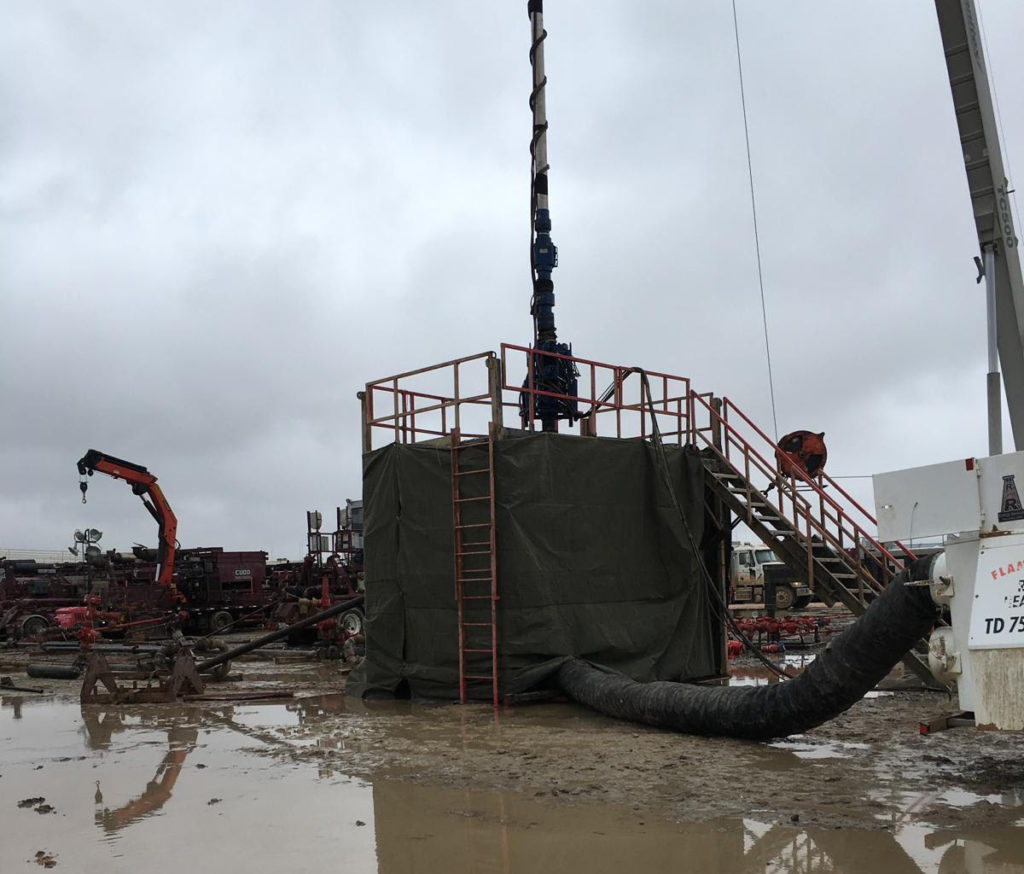 A crane is lifting a large pipe into the ground.