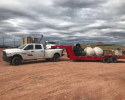 A white truck pulling two large balls on top of a trailer.